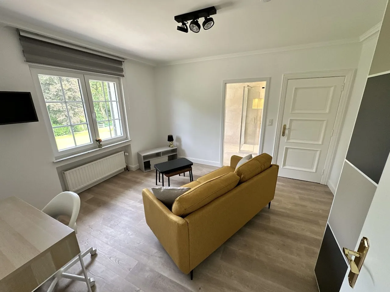Suite privative avec canapé jaune moutarde et accès salle de douche, coliving Condroz